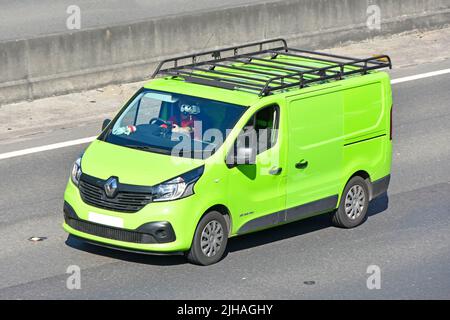 Close up side front & aerial view lime green colour clean unmarked Renault van roof rack driver driving along UK motorway road concrete crash barrier Stock Photo