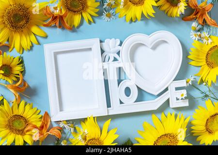 Photo frame, sunflower, lily and chamomile photo frame with copy space on pastel blue background. Minimal concept. Stock Photo
