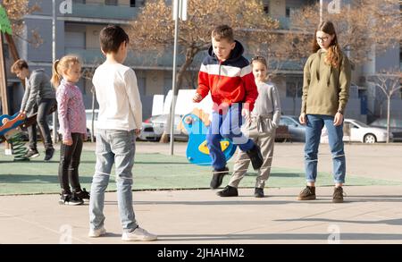 Energetic kids playing and skipping on elastic jumping rope in european yard Stock Photo