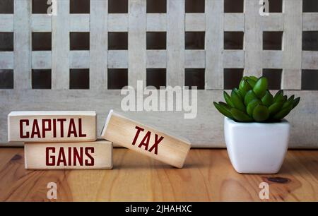 CAPITAL GAINS TAX - words on wooden blocks on a beautiful background. Business and hybrid work culture concept, copy space. Stock Photo