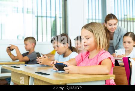 Pupils using mobile phones during lesson in school Stock Photo