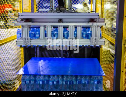 Robot arm lifting packages bottle of water in water bottling line. Stock Photo