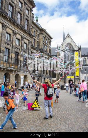 AMSTERDAM, NETHERLANDS, - July 17, 2015: Street artist blowing bubbles for the tourists on the dam in Amsterdam Stock Photo