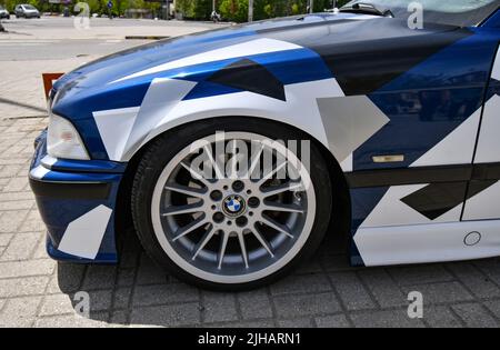 View of the sport car BMW 3 e36 cabriolet with sport rims and covered with decals parked in the street. Stock Photo