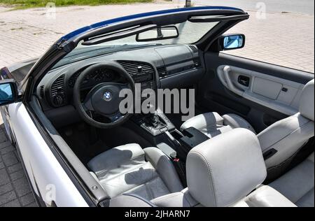 View of the sport car BMW 3 e36 cabriolet with sport rims and covered with decals parked in the street. Stock Photo