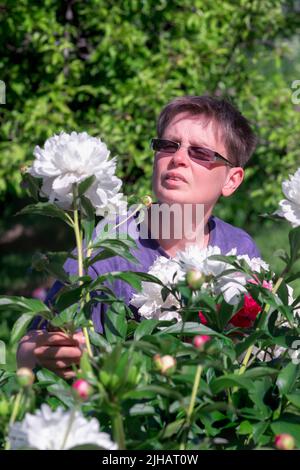 Woman wint peony flowers in a garden Stock Photo