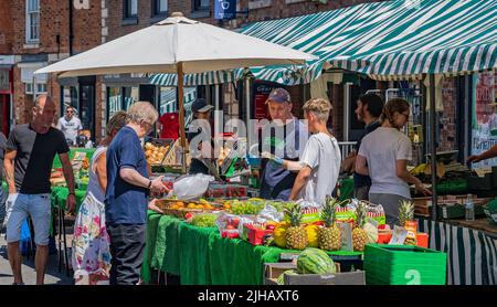 Grantham, Lincolnshire, UK – Shoppers at the traditional street market held in the town selling produce and vegetables plus fruit Stock Photo