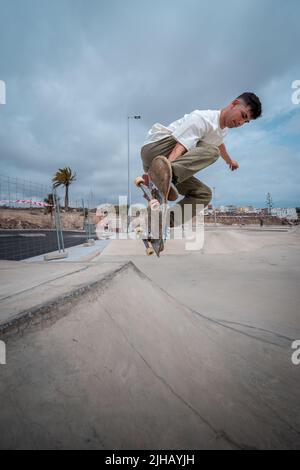 young skateboarder jumps over a ramp in a skate park Stock Photo