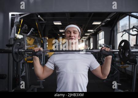 Strong healthy young man doing push press exercise with barbell Stock Photo