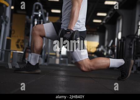 Cropped shot of unrecognizable athletic man doing lunges with dumbbells at gym Stock Photo