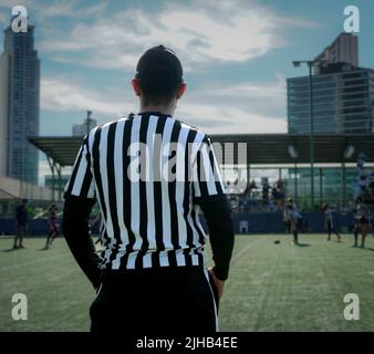 A rear view of a male referee in a field on a sunny day Stock Photo