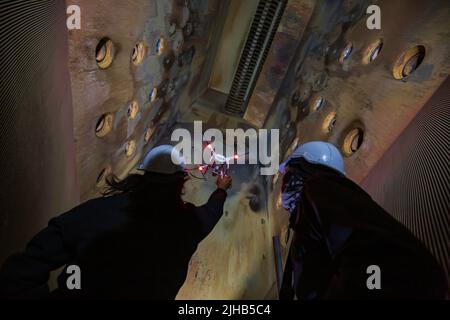 Drone male inspection operated by construction worker on furnace in confined site Stock Photo