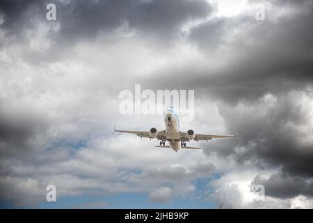 A low angle view of a TUI aircraft landing in stormy weather and turbulence with black clouds in a flight and vacation issues concept Stock Photo