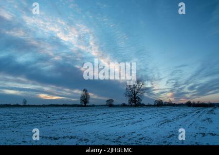 Snow-covered field and cool clouds in the evening, winter view Stock Photo