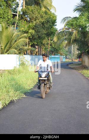 An indian young man riding a motorcycle near a paddy field Stock Photo