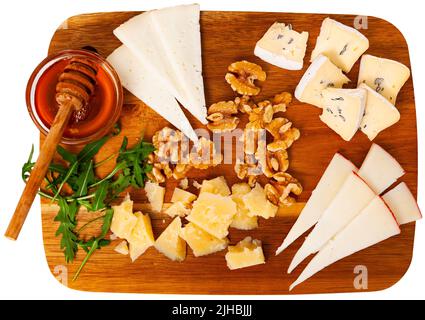 Cheese platter with honey, walnuts, arugula served on wooden board Stock Photo