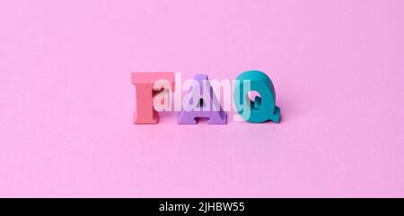 wooden colorful capital letters FAQ on pink background Stock Photo