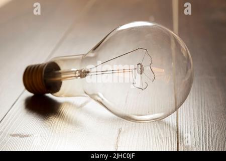 view of a burned out incandescent light bulb, placed on a wooden surface Stock Photo