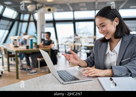Young happy Asian business woman using laptop conferencing in office. Stock Photo