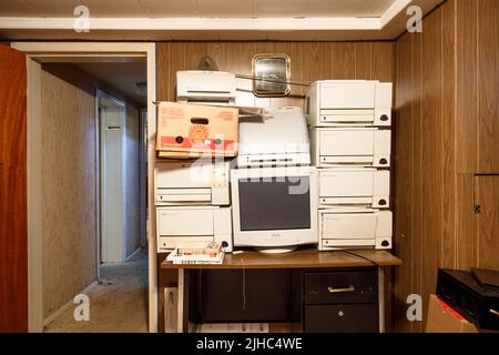 An outdated computer monitor and printers sitting on a retro desk. Stock Photo