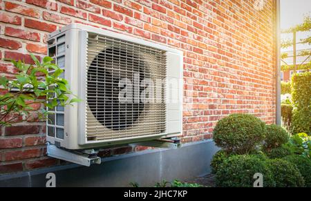 Air conditioning heat pump outdoor unit against brick wall. Stock Photo