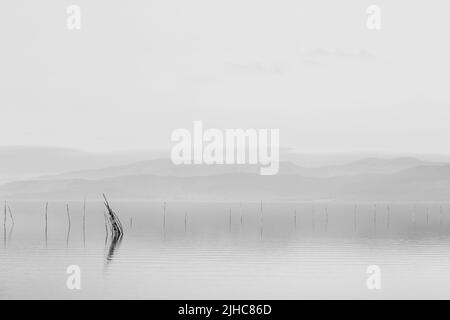 https://l450v.alamy.com/450v/2jhc86d/minimalist-view-of-fishing-net-poles-on-a-lake-with-perfectly-still-water-and-empty-sky-at-dusk-2jhc86d.jpg