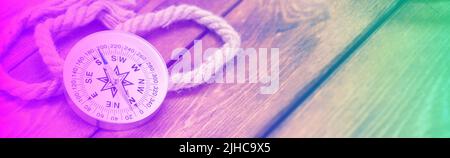 Compass and rope on wooden texture background in neon light Stock Photo