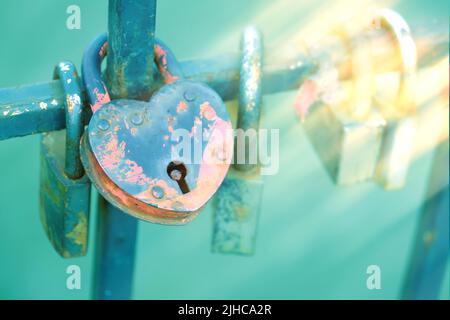 The railing of the bridge with love locks. Heart-shaped castle in the foreground Colorful castles with an inscription. The oath of the newlyweds in Stock Photo