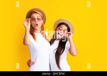 Studio portrait of funny child with mum. Funny face. Mom and teenager daughter hugging lovely cuddling, wearing white t-shirts straw hat and Stock Photo