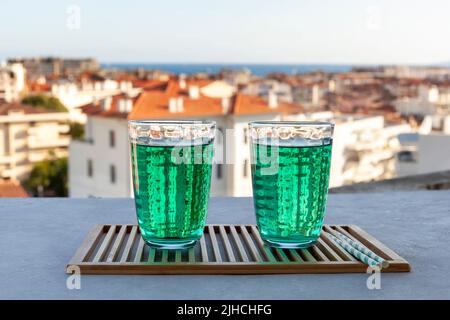 two transparent glasses of Diabolo menthe, popular non-alcoholic cold french drink on the summer sea city background Stock Photo