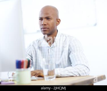 Focusing on the finer details. a serious-looking african american designer at work on a desktop computer in the office. Stock Photo