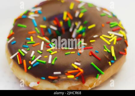 chocolate coated doughnut or donut with sprinkles on in close up Stock Photo