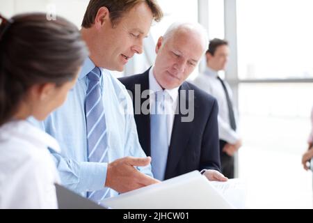Going through the finer print together. Focused businesspeople going through documents together in an informal meeting. Stock Photo