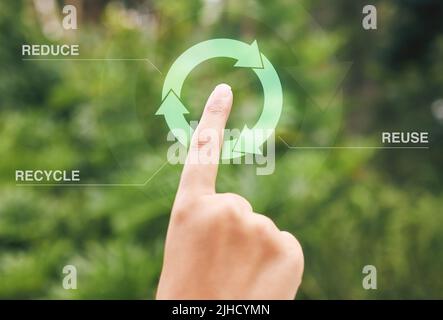 Finger selecting a digital recycle symbol. A digital recycling button being pressed by a person. Using technology to recycle, reuse and reduce waste. Stock Photo