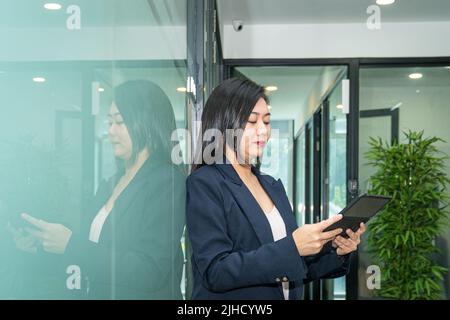 Beautiful businesswoman looking down at her digital tablet. Office setting. Stock Photo