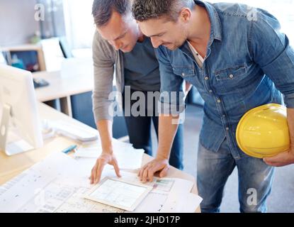 Dreams in development. two architects working together on a blueprint with the help of a digital tablet. Stock Photo