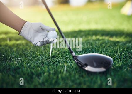 Im sorry but Im going to hit you far away. Closeup shot of an unrecognizable person putting a golf ball on top of a golf peg with a golf club standing