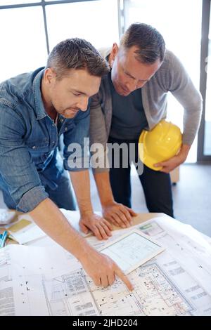 Plans in progress. two architects working together on a blueprint with the help of a digital tablet. Stock Photo