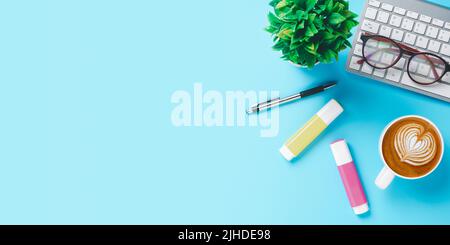 Office desk with keyboard, Pen, eyeglass, Cup of coffee on blue background, Top view with copy space, Mock up. Stock Photo
