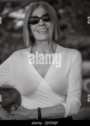 senior fit elegant lady dressed blaka dn white wearing sunglasses enjoying nature in summer Stock Photo