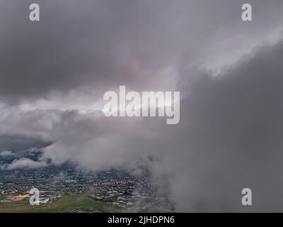 Flying through thick clouds. Rain clouds in the sky. Cumulus clouds, meteorology and climate studies.Photo of the city from the height of clouds, aeri Stock Photo