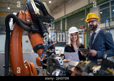 Female engineering manager and mechanic worker doing routine check up in industrial factory Stock Photo