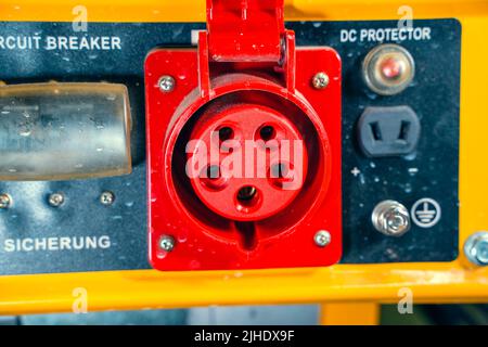 Industrial red power socket with earth close-up. Gasoline generator housing Stock Photo