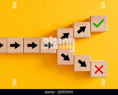 Arrow symbols on wooden cubes splitting into different directions towards right or wrong choices. Following the right or wrong path or choosing the ri Stock Photo