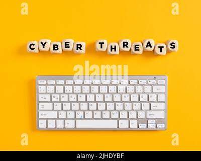 The word cyber threats with computer keyboard on yellow background. Cyber attack and security concept. Stock Photo