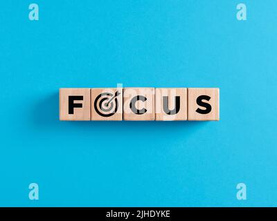 The word focus on wooden cubes with target icon. Focusing or concentrating on business objectives, goals or marketing target customers concept. Stock Photo