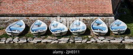 Small white boats lined up beside a historic brick wall in Holíč, Slovakia. Stock Photo
