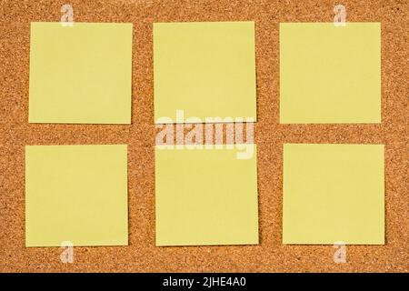 Six empty yellow sticky notes on a cork board, copy past Stock Photo