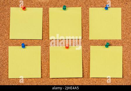 Six empty yellow sticky notes on a cork board with drawing pins, copy past Stock Photo