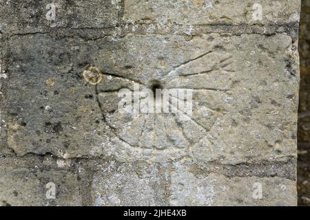 Medieval mass dial or scratch dial on the exterior of the church of St Mary Magdalene, Geddington, Northamptonshire, UK Stock Photo